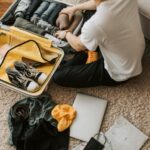 Man packing clothes and footwear into suitcase for travel.