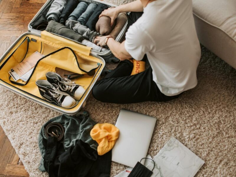 Man packing clothes and footwear into suitcase for travel.