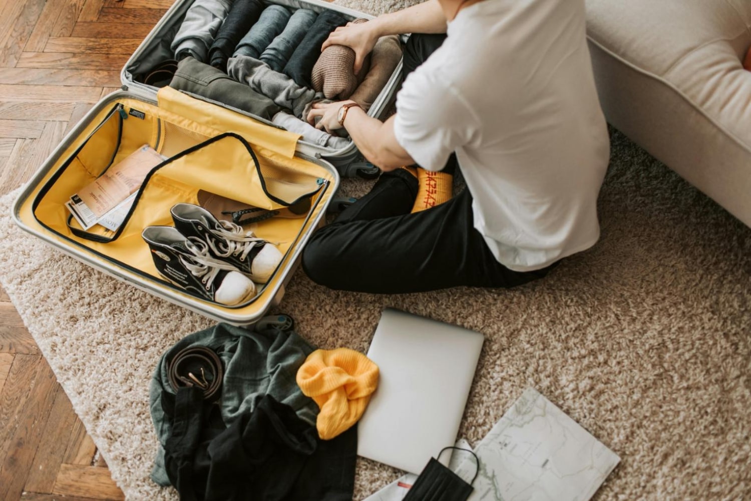 Man packing clothes and footwear into suitcase for travel.